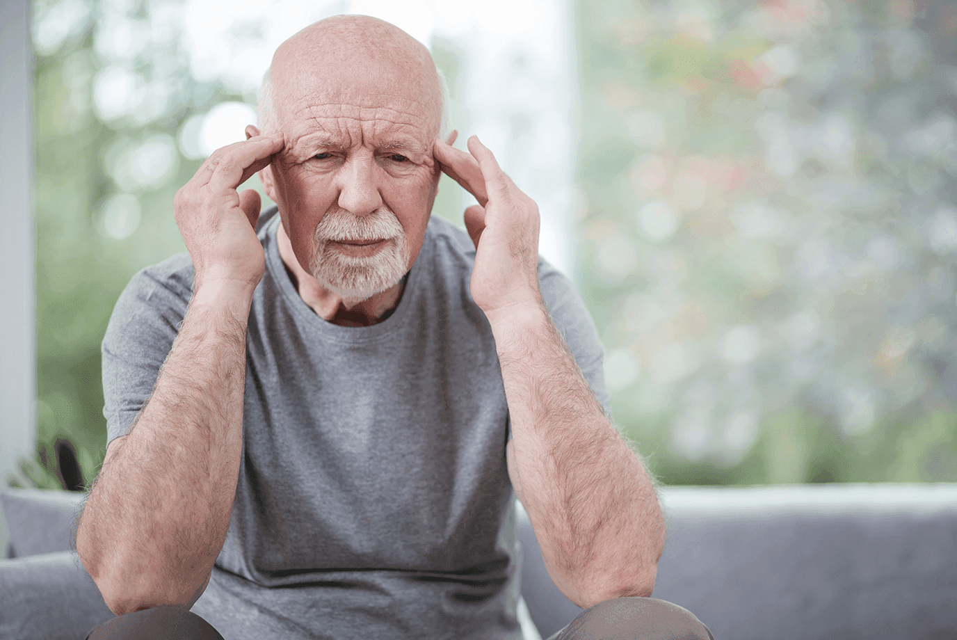 Older man holding his head because of a migraine